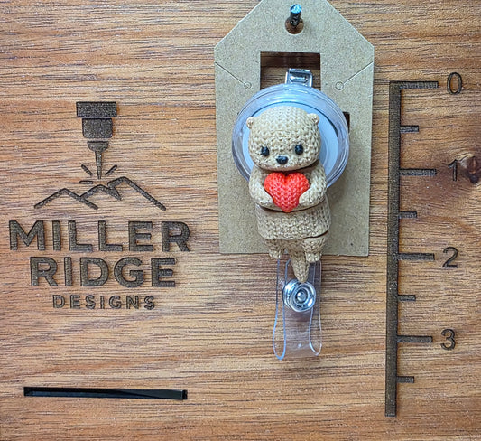 Otter holding heart badge reel