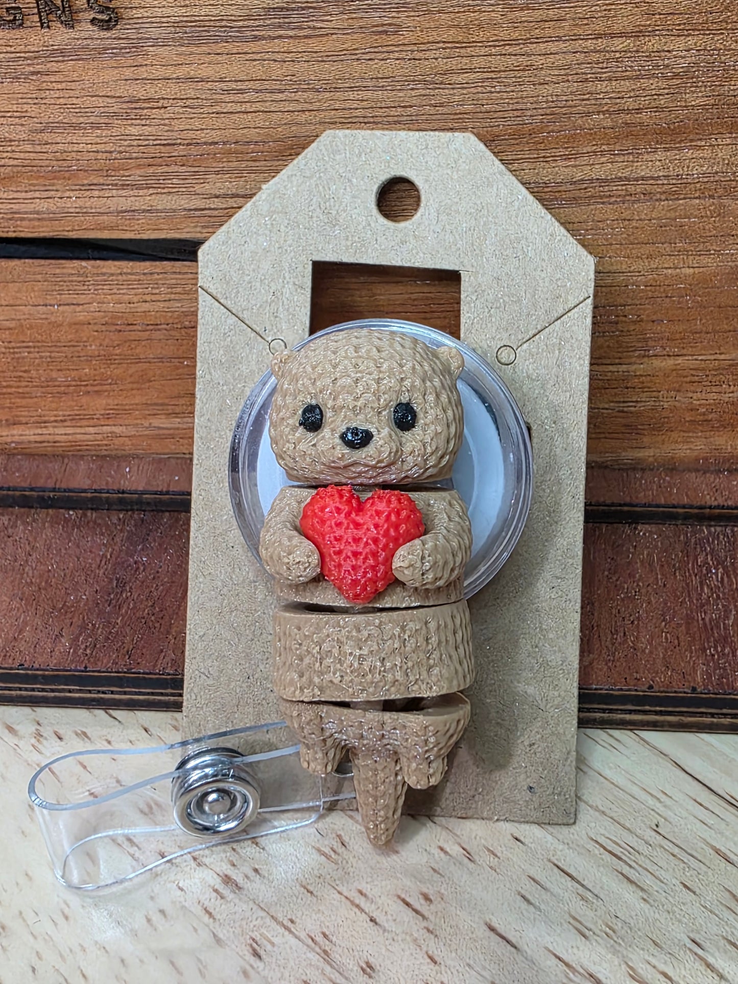 Otter holding heart badge reel