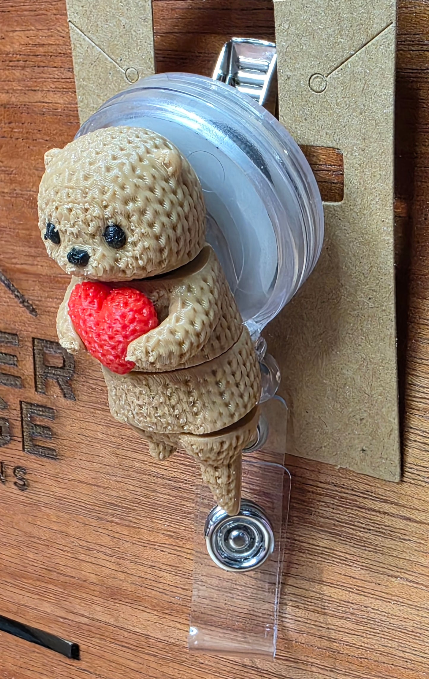 Otter holding heart badge reel